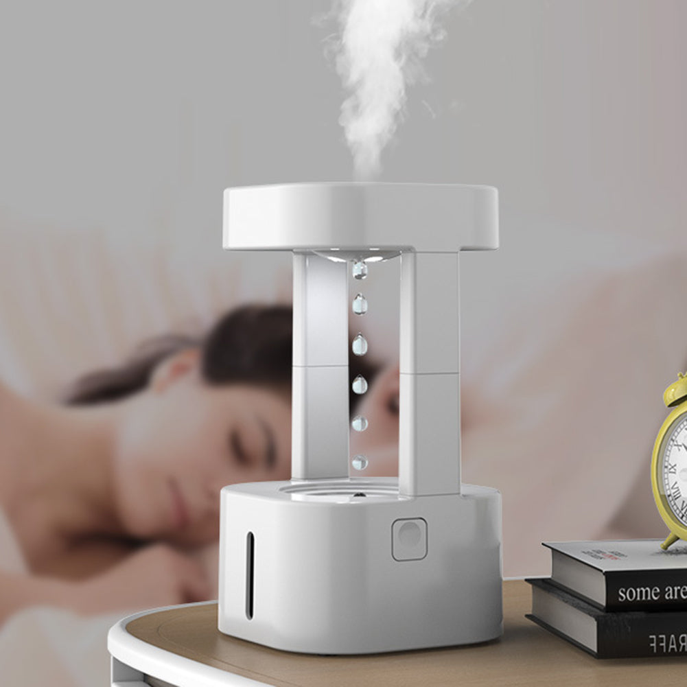 White ultrasonic humidifier emitting mist on bedside table with books and alarm clock, ideal for home comfort