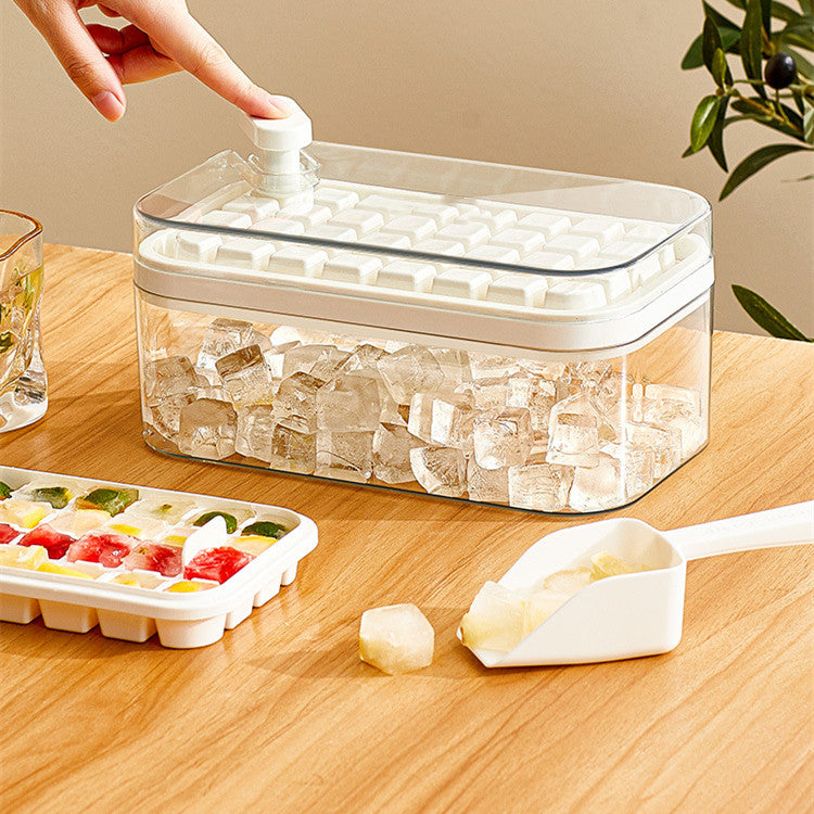 Clear ice cube storage container with lid, scoop, and silicone tray on wooden table